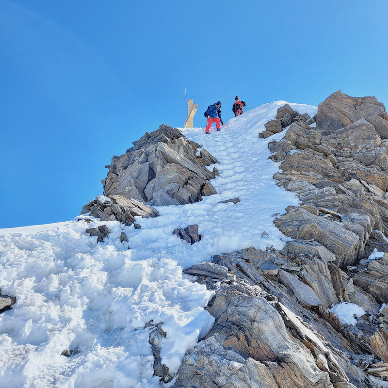 Austrian mountain and ski guide short roping his client near by a summit.